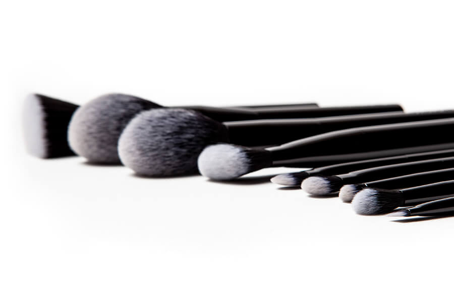 Crunchi brush being dipped in a canister of Crunchi eyeshadow